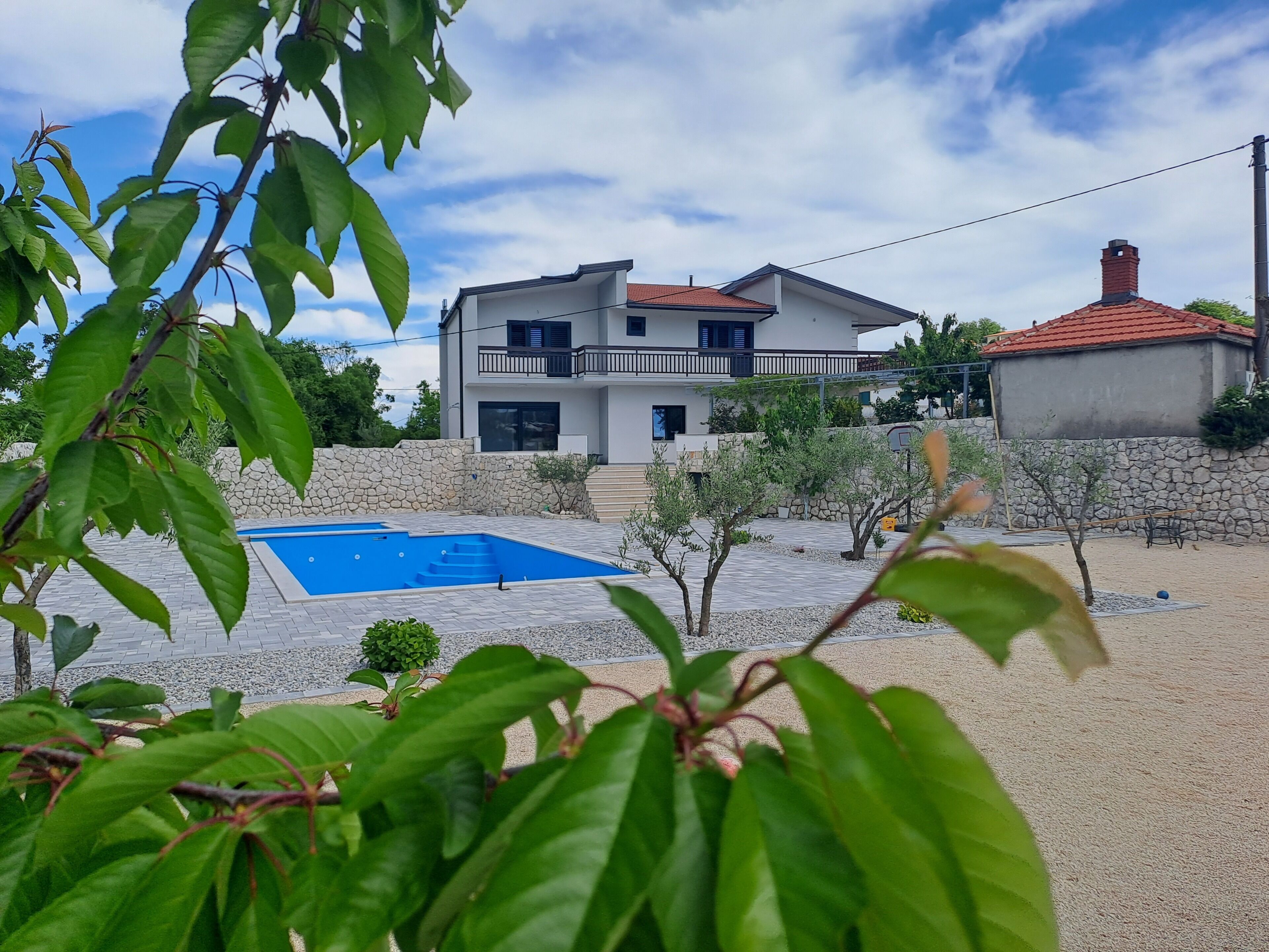 A two-story house with a swimming pool, stone walls, and a balcony.