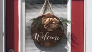 A red door with a welcome sign and a window with blinds. - Caddy Corner has a hot tub just outside of town (French Lick)