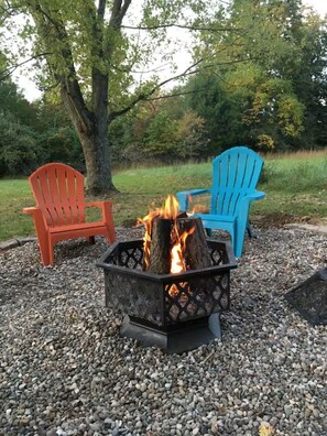 Ein Feuerkorb mit zwei Adirondack-Stühlen, umgeben von Kies.