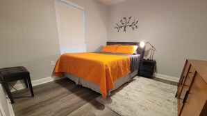 Un dormitorio con cama, mesita de noche, lámpara y cómoda.