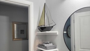 Un baño con un modelo de barco, toallas y un espejo.