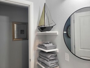 Un baño con un modelo de barco, toallas y un espejo.