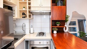 A modern kitchen with a built-in oven, a stovetop, and wooden cabinetry. - San Isidro 635 (Santiago)
