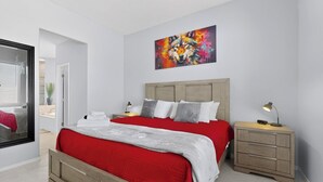 A bedroom with a large bed, a nightstand, a bedside table, a mirror, and a painting on the wall. - Palomar: New Build, Hot Tub, Pet-Friendly, BBQ (Albuquerque)
