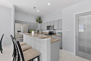 Eine moderne Küche mit Granit Arbeitsplatten, Edelstahlgeräten und einer Bar.