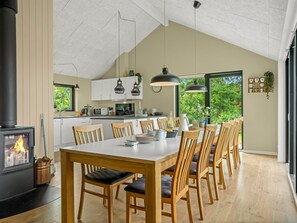 Eine moderne Küche mit einer zentralen Kochinsel, Holzstühlen, Pendelleuchten und einem sichtbaren Kamin.