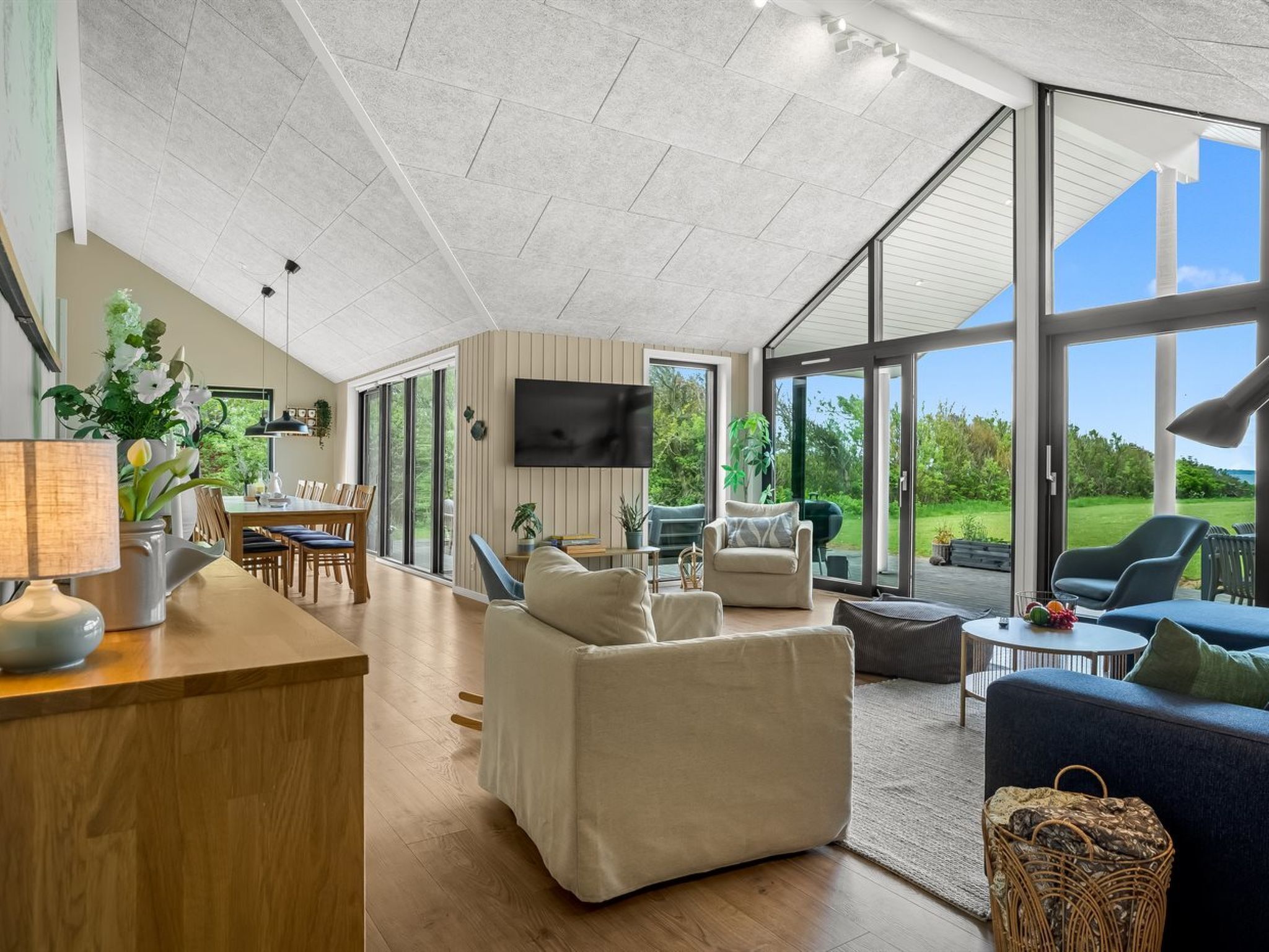 A spacious living area with a dining table, sofas, and a TV.