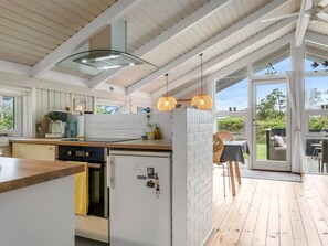 Eine moderne Küche mit eingebautem Geschirrspüler, einem großen Fenster und einer Glastür, die zu einem Sitzbereich im Freien führt.
