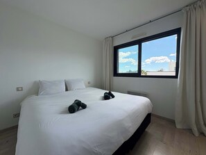 Una habitación de hotel con una cama grande, un ventanal con vistas y un radiador.