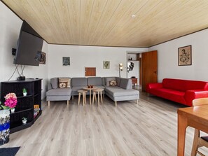 A modern living room with a grey sectional sofa, a red couch, a TV on a stand, and a wooden ceiling. - "Tessa" - 19km from the sea by Interhome (Højer)