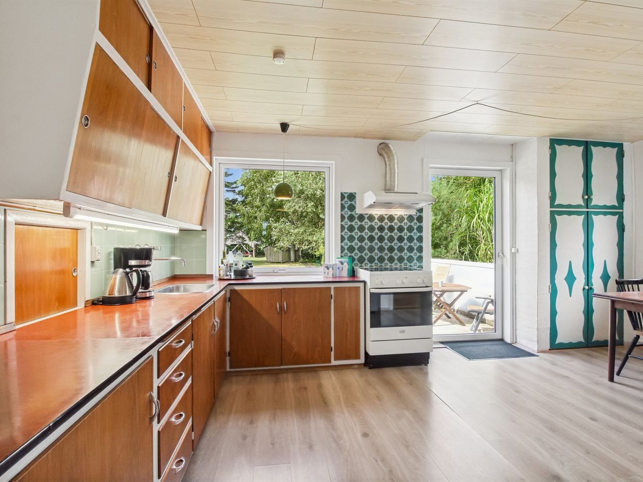 A modern kitchen with wooden cabinets, a built-in oven, and a view to the outdoors.