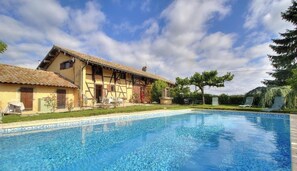A swimming pool with a traditional building in the background. - Le Clos de l'Orme - BOISSEY (BOISSEY)
