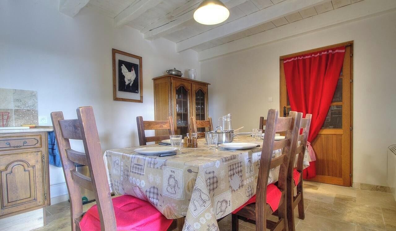 A dining room with a table set for four, wooden chairs, a cabinet, and a red curtain.