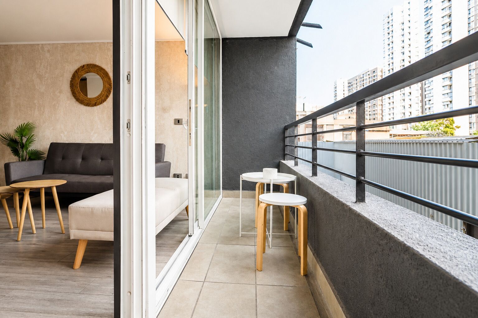 A modern apartment with a balcony, a sofa, two tables, and a potted plant.
