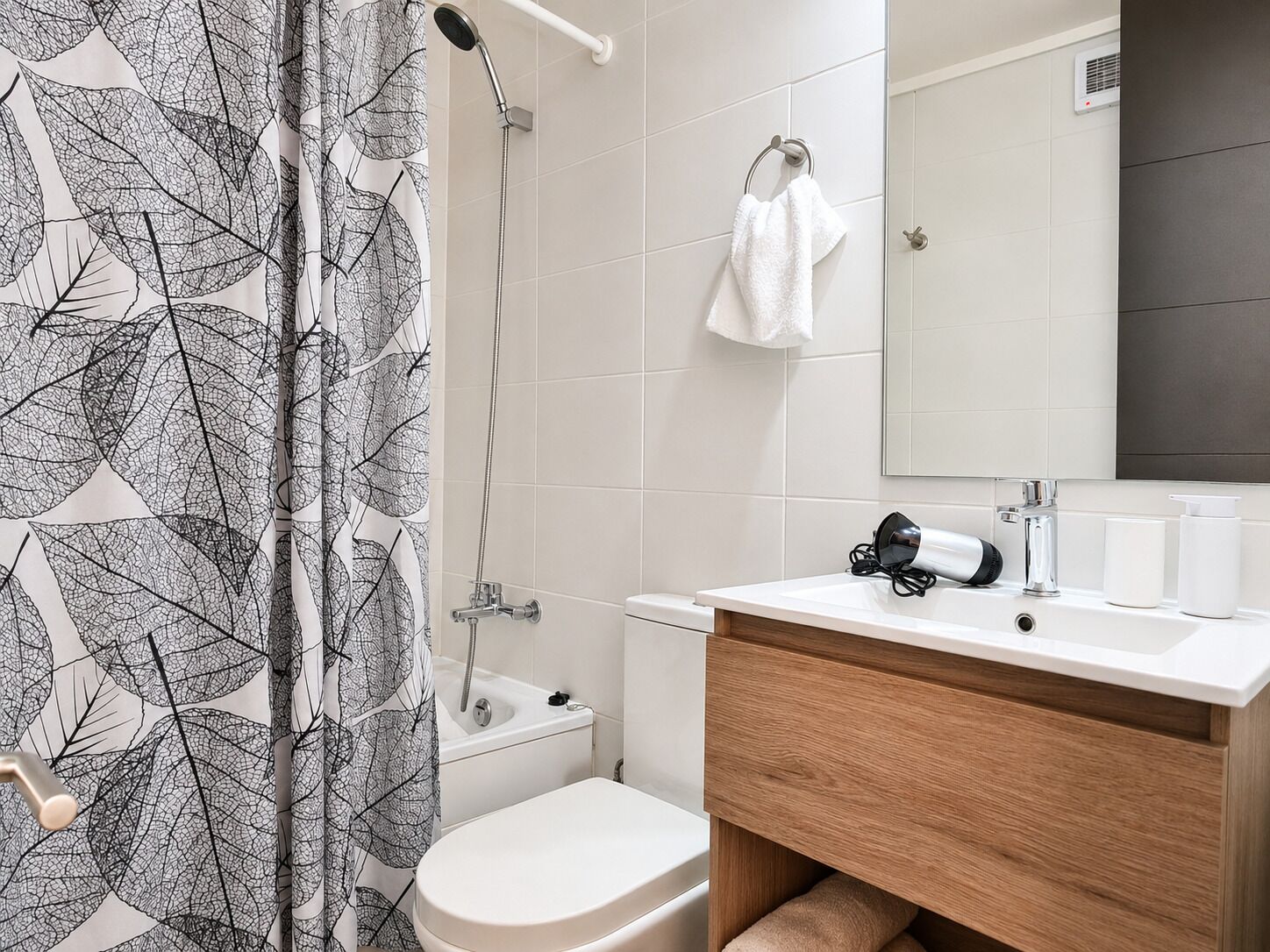 Un baño con ducha, inodoro y lavamanos con un espejo encima.