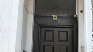 Una porta negra amb el número '9' a dalt, una petita presència d'aire a la part superior de la porta i un rell de porta al costat esquerre.