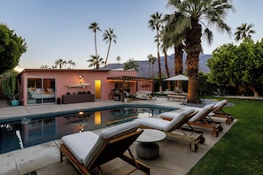 A pool area with lounge chairs, a pool, and a building with large windows and a door. - The Retreat, Private MidCentury home in sunny Palm Springs (Palm Springs)