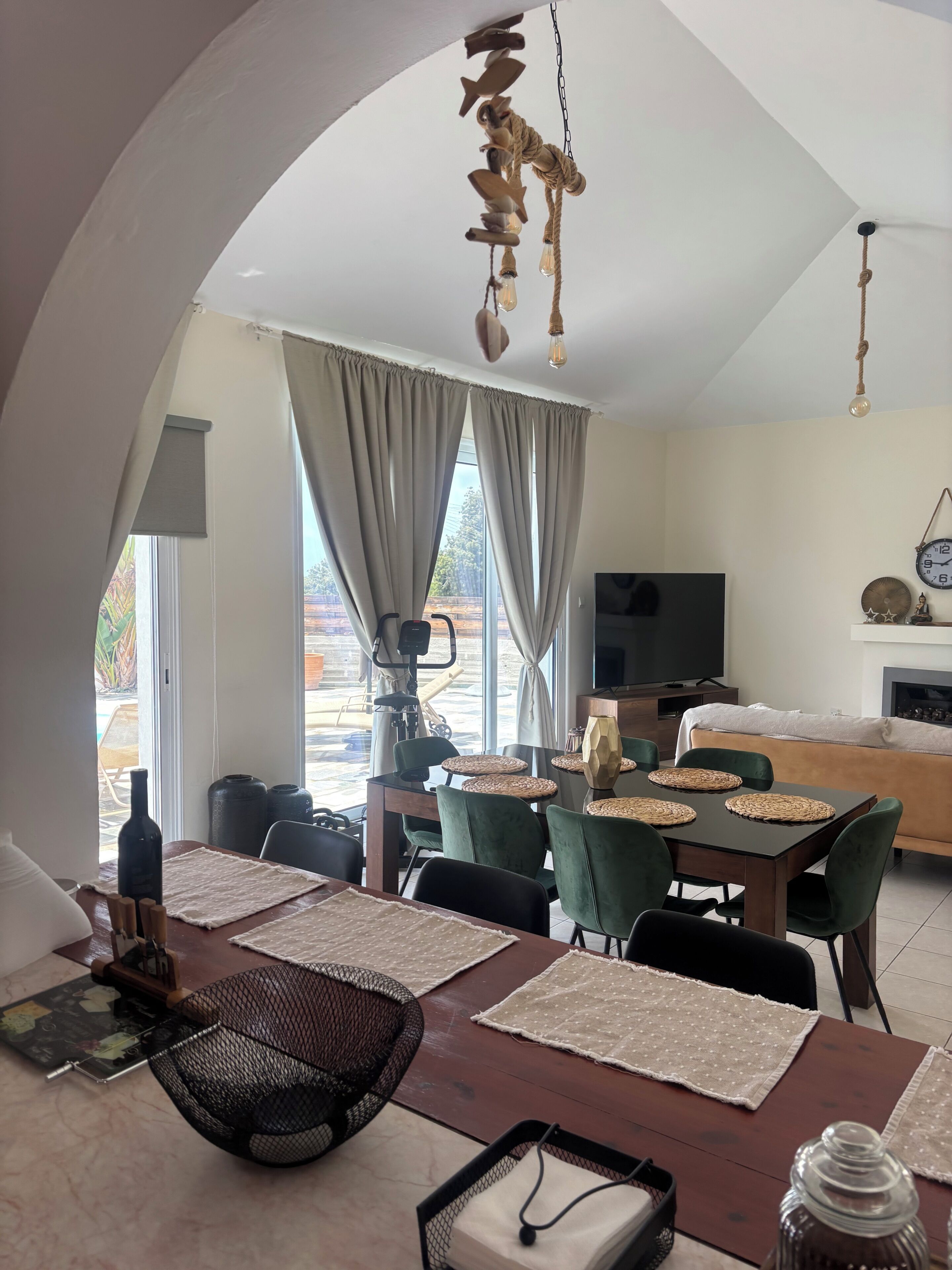 Ein modernes Wohnzimmer mit Essbereich, großen Fenstern und einem Fernseher.
