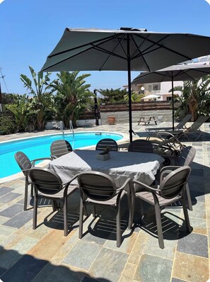 A poolside area with a round table and chairs, a large umbrella, and a pool. - RELAX IN A PRIVATE 3 BEDROOMS BUNGALOW WITH SWIMMING POOL. (Paphos)