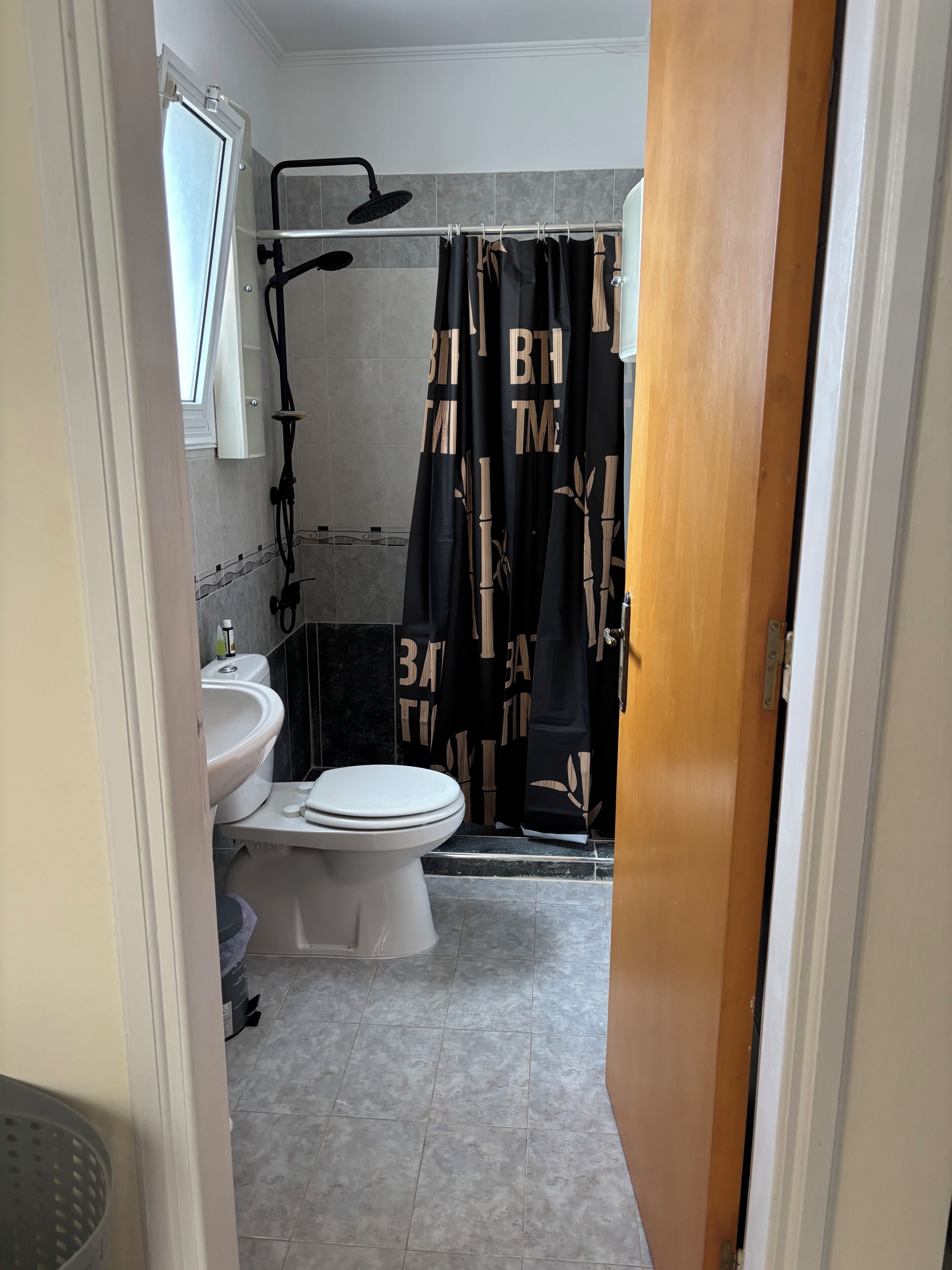 Une salle de bain avec des toilettes, un lavabo, une douche et une fenêtre.