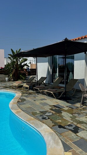 A swimming pool with lounge chairs and a covered seating area. - RELAX IN A PRIVATE 3 BEDROOMS BUNGALOW WITH SWIMMING POOL. (Paphos)