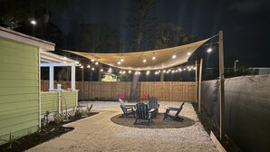 Eine Terrasse mit Tisch und Stühlen, einem Holzzaun und Lichterketten.