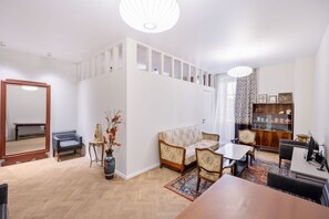A modern living room with a sofa, a coffee table, a dining table, and a bookshelf. - Tbilisi Legend – Rustaveli 37 (T'bilisi)