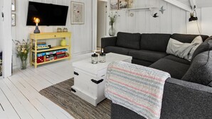 Un salon avec un canapé, un téléviseur, une bibliothèque et une cheminée.