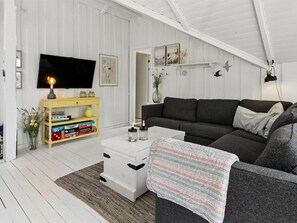 Ein Wohnzimmer mit einer Couch, einem Fernseher, einem Bücherregal und einem Kamin.