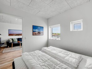 Un dormitorio con cama, ventana y un cuadro en la pared.