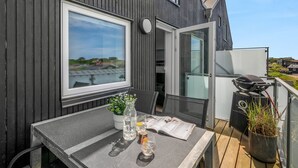 Un balcon avec une table, un barbecue, une fenêtre et une porte.