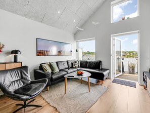 A modern living room with a leather sofa, a coffee table, and a large window offering a view of the landscape. - "Halldora" - 300m from the sea by Interhome (Ringkøbing)