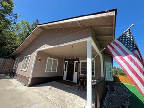 Ein Haus mit Veranda, einer Flagge und einem Holzzaun.