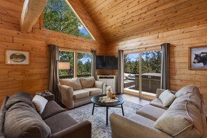 Interior de una cabaña de madera con sofá, mesa de centro y televisor.