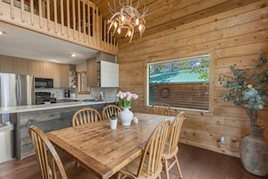 Ein Holzblockhaus-Interieur mit Küche, Essbereich und einem großen Fenster.