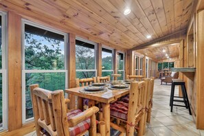 A wooden dining area with a table set for four, surrounded by chairs with plaid cushions.