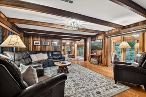 A spacious living room with a leather sofa, a round coffee table, and a patterned rug.