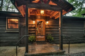 A wooden cabin with a porch, a door, and a window.