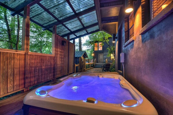 A hot tub with a wooden deck and a covered area with a metal roof.