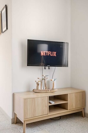 Un téléviseur fixé au mur, avec un meuble en bois placé en dessous.