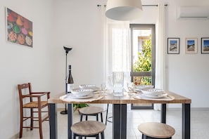 Een eetgedeelte met een houten tafel, stoelen, een karaf en kommen.