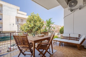 Een balkon met een houten tafel, stoelen en een bank.
