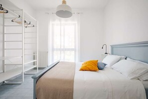 Ein Schlafzimmer mit Bett, Kleiderschrank, Fenster und Deckenleuchte.