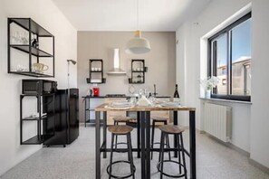 Eine moderne Küche mit Essbereich, schwarzem Metallregal und einem großen Fenster.