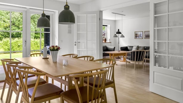 Un'ampia stanza con un tavolo da pranzo in legno, sedie e lampade a sospensione.