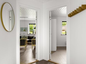 Ein Zimmer mit Holzboden, einer weißen Tür, einem Spiegel, einem Fenster und einer Treppe.