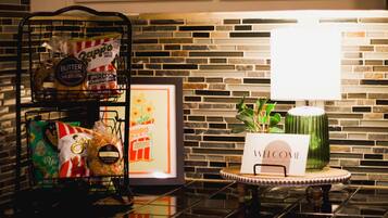 A kitchen counter with a metal rack holding snacks, a framed picture, and a welcome sign on a small table.