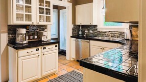 A kitchen with white cabinets, a black countertop, and a tiled backsplash.