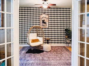 Una habitación con un estampado de cuadros en la pared, un sillón colgante, una mesita y una alfombra.