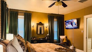 A bedroom with a bed, a television, a desk, and a chair.